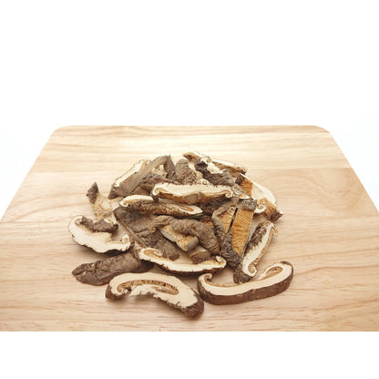 Häufchen geschnittener shiitake pilze auf einem hellen Holzbrett, pilzscheiben in unterschiedlicher Größe.