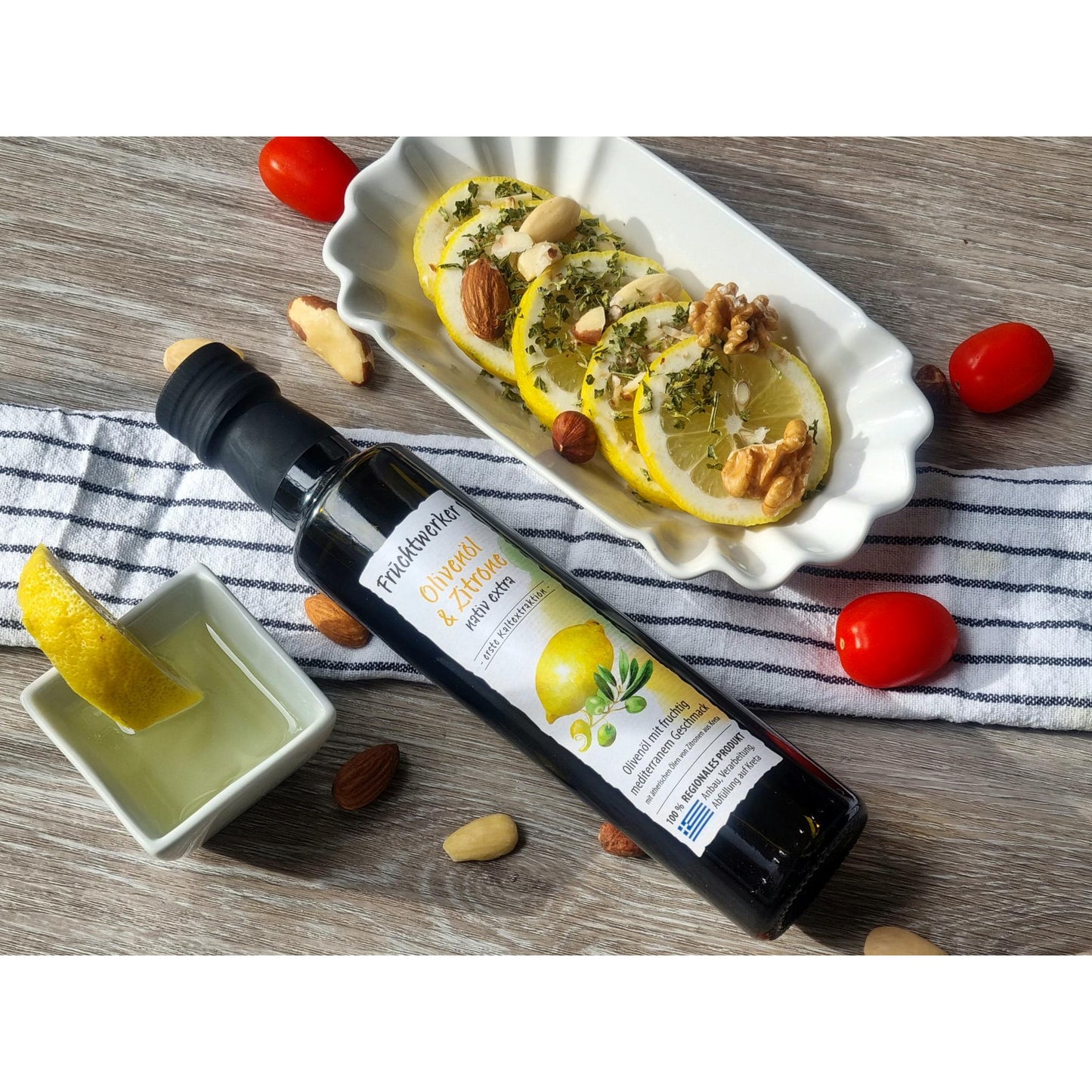 Fruchtwerker Olivenöl mit Zitrone 250ml auf einem Holztisch neben Zitronenscheiben mit Nüssen, Tomaten und einem Schälchen mit Zitronenstück, ideal zum Kochen.
