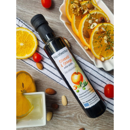Fruchtwerker Olivenöl + Orange 250ml auf Holz, neben Orangenscheiben mit Nüssen, Tomaten, Mandeln und einem Schälchen Öl, Arrangement für Öle & Säfte.