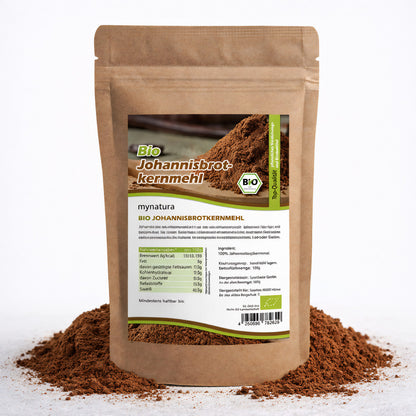 Beutel mit Etikett für Bio Johannisbrotkernmehl E410, stehend auf einem Haufen braunen Mehls, Produkt für backen, kochen und als glutenfreies verdickungsm geeignet.
