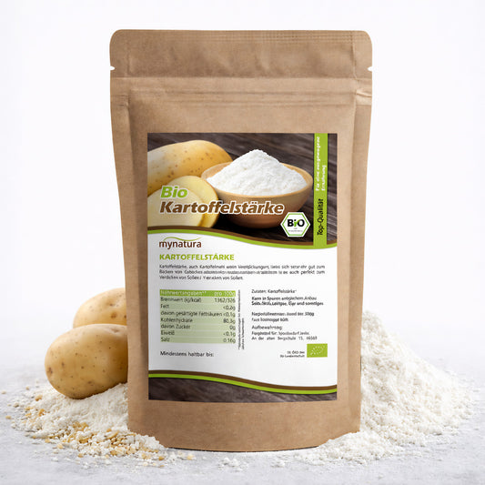 Beutel Mynatura Bio Kartoffelstärke 500g vor Kartoffeln und einem Holzschälchen mit weißer Stärke auf verstreuter glutenfreier Stärke
