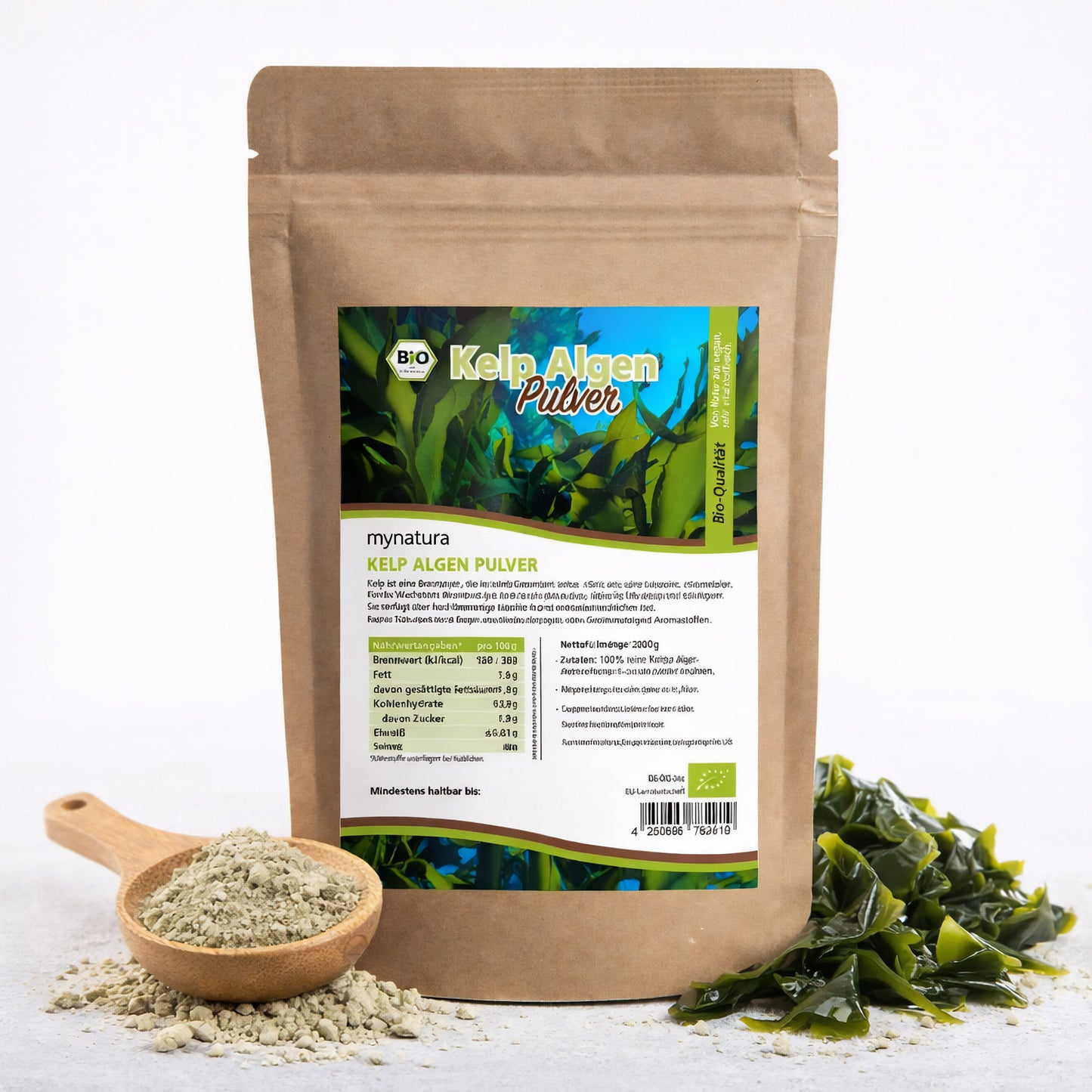 Beutel mit Bio Kelp Algenpulver von mynatura, daneben Holzlöffel mit pulver und frische Algen, geeignet für kreative rezeptideen.