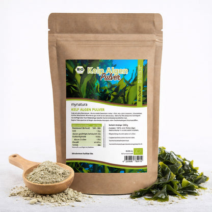 Beutel mit Bio Kelp Algenpulver von mynatura, daneben Holzlöffel mit pulver und frische Algen, geeignet für kreative rezeptideen.