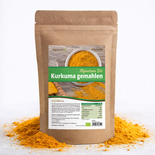 Beutel Mynatura Bio Kurkuma Pulver stehend auf weißem Hintergrund, umgeben von verstreutem gelbem Pulver, Vorderseite mit Etikett sichtbar.
