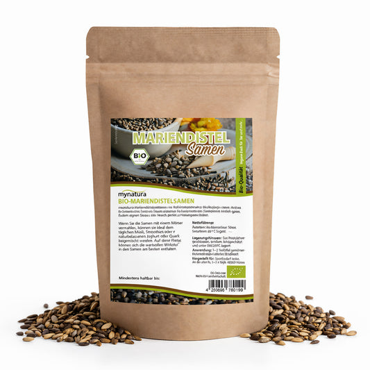 Beutel mit mynatura Bio Mariendistelsamen, 500g, naturbelassen, aufrecht stehend, umgeben von losen Samen auf weißem Hintergrund.