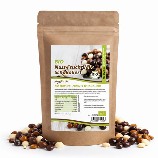 Beutel Mynatura Bio Nuss-Fruchtmischung schokoliert 500g, stehend, umgeben von bunten schokolierten Nüssen und Früchten auf weißem Hintergrund.