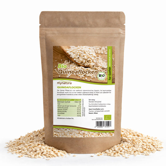 Beutel mit mynatura Bio Quinoaflocken, umgeben von losen Quinoaflocken, Vorderseite mit Produktetikett und Nährwertangaben, geeignet fürs Frühstück und Backen.