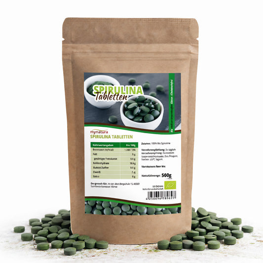 Beutel mit mynatura spirulina tabletten, 500g, stehend auf weißem Untergrund, grüne Tabletten rundherum verteilt