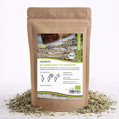 Beutel mit Bio Wermutkraut, geschnitten, 100g, von Mynatura, stehend auf einer Unterlage aus losem kraut, Vorderseite mit Etikett und Zubereitungshinweisen sichtbar.