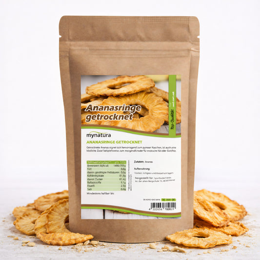 Beutel mit getrocknete Ananasringe von Mynatura, stehend auf weißem Untergrund, umgeben von mehreren Ananasringe als Snacks.