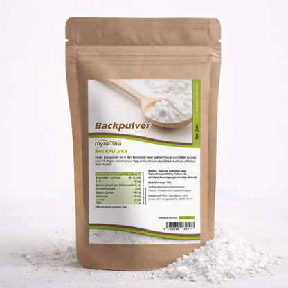 Beutel mit Mynatura Backpulver 250g, vorne Etikett mit Nährwertangaben und Holzlöffel mit feinem Pulver, Pulver ist teilweise vor dem Beutel verstreut.