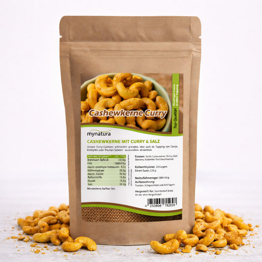 Offener Beutel mit Mynatura Cashewkernen, gewürzt mit Curry und Salz, umgeben von verstreuten knusprigen Nüssen als veganer Snack auf weißem Untergrund.
