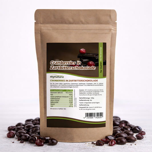 Beutel mit Etikett für Mynatura Cranberries in Zartbitterschokolade, stehend auf weißem Untergrund, umgeben von einzelnen fruchtig-herben Snacks und Schokoladenstückchen.
