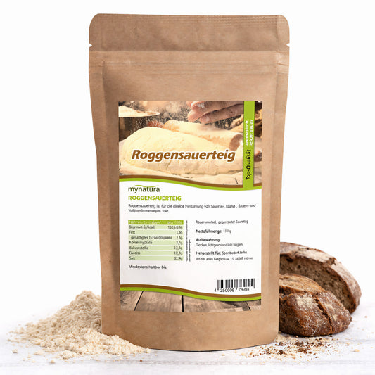 Beutel Roggensauerteigpulver von Mynatura mit sichtbarem Etikett, daneben Roggenbrot und etwas Pulver auf weißem Untergrund.