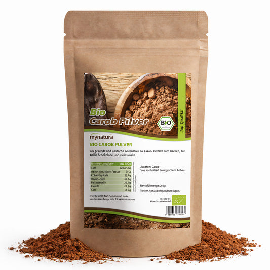 Beutel mit mynatura Bio Carobpulver, 250g, stehend auf verstreutem Pulver, Vorderseite mit Etikett und Nährwertangaben sichtbar.