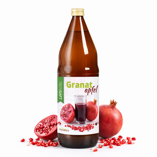 Braune Flasche Granatapfel Direktsaft mit Etikett, umgeben von frischem Granatapfel, einer Hälfte und Kernen auf weißem Hintergrund.