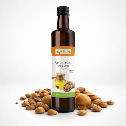 Braune Glasflasche Aprikosenkernöl 250ml von mynatura, umgeben von Aprikosenkernen auf weißem Hintergrund.