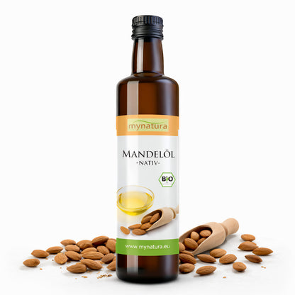 Braune Glasflasche Mynatura Mandelöl kaltgepresst, 250ml, stehend vor Mandeln und Holzschaufel auf weißem Hintergrund.