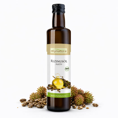 Braune Glasflasche Rizinusöl von Mynatura, stehend vor Rizinussamen und grünen Rizinusfrüchten auf weißem Hintergrund.