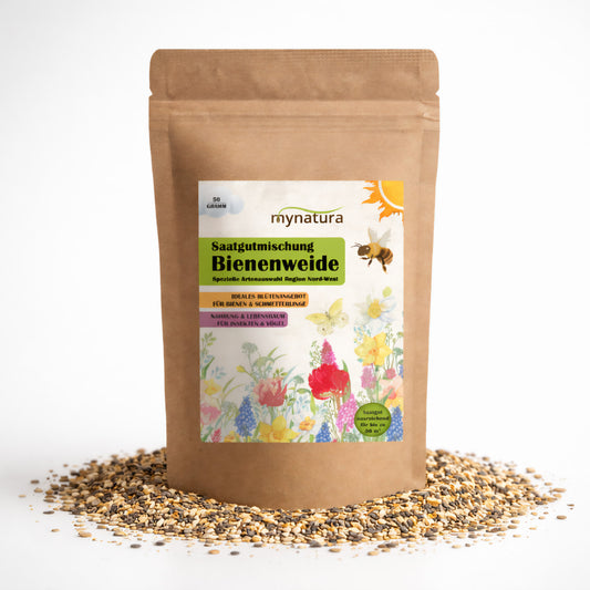 Beutel mit Mynatura Bienenweide Nord-West Bienen 50g auf weißem Hintergrund, umgeben von verstreuten Blumensamen für Garten oder Wiesenfläche.
