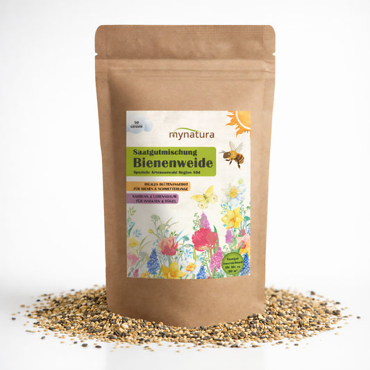 Beutel Mynatura Bienenweide mit 50g Blumensamen, stehend auf verstreuten Samen, Vorderseite mit bunter Blumenillustration und Bienenmotiv.