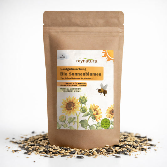 Braune Tüte Mynatura Bio Sonnenblumen Saatgutmischung mit illustrierten Sonnenblumen und Biene auf dem Etikett, umgeben von verstreutem Sonnenblumen Saatgut.