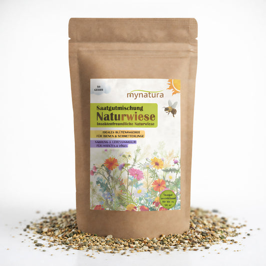 Vorderseite der Mynatura Saatgutmischung Naturwiese im braunen Standbeutel, umgeben von verstreuten Blumensamen auf weißem Hintergrund.