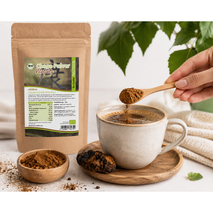 Chagapulver wird mit einem Holzlöffel in eine Tasse mit Getränk gegeben, daneben Beutel Bio Chaga Pulver, Schale mit Pulver und Chaga Pilz auf Holzuntersetzer.