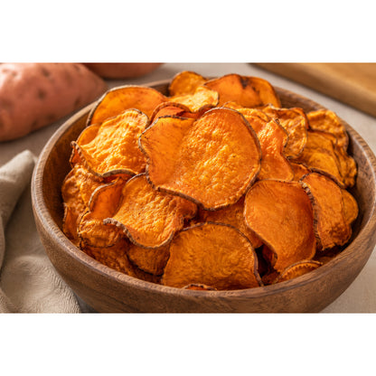 Holzschale gefüllt mit knusprigen ofengerösteten süßkartoffelchips, im Hintergrund angeschnittene süßkartoffel