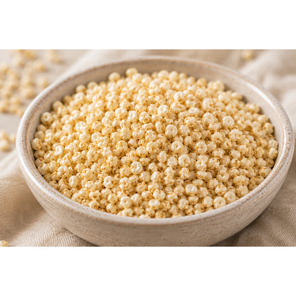 Nahaufnahme einer Schale mit gepufftem Quinoa als veganer Superfood-Snack auf hellem Stoff.