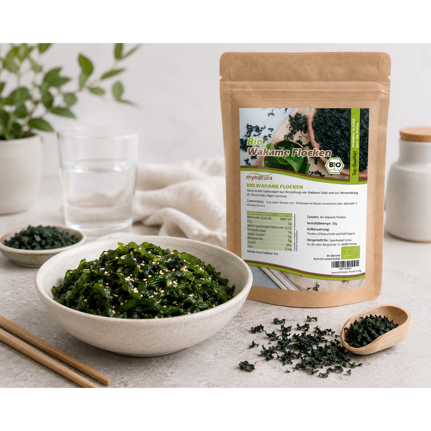 Bio Wakameflocken von Mynatura im Beutel, daneben eine Schale mit zubereitetem Wakame-Salat und Essstäbchen auf hellem Tisch.