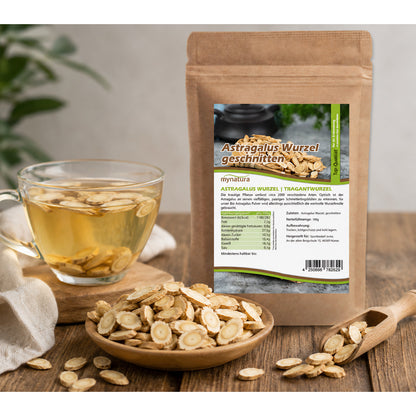 Tasse mit Tee und eingelegten Scheiben der geschnittenen Astragaluswurzel neben einer braunen Verpackung mit Produktetikett und Holzschale auf Holztisch