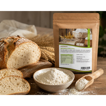 Weizengluten Vital Beutel von mynatura neben einer Schale mit Pulver, Holzlöffel und angeschnittenem Brot auf einem Holztisch.