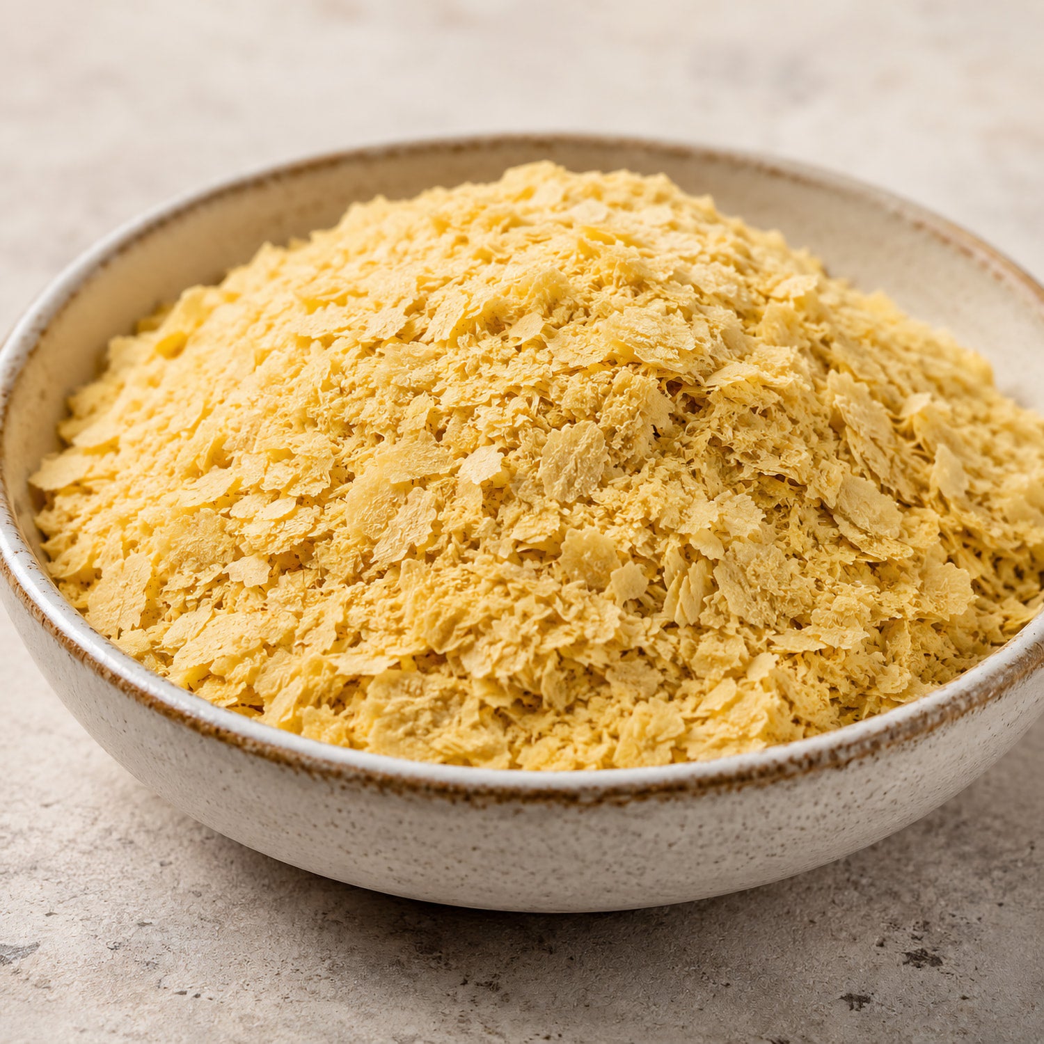 Schale mit gelben hefeflocken, superfood in flockiger Form, auf hellem Untergrund, hefeflocken deutlich sichtbar.