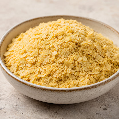 Schale mit gelben hefeflocken, superfood in flockiger Form, auf hellem Untergrund, hefeflocken deutlich sichtbar.