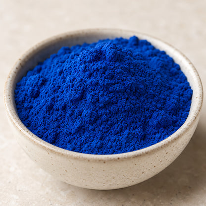 Schale mit intensiv blauer Spirulinapulver-Füllung, Pulver fein gemahlen und leuchtend blau, auf hellem Untergrund.
