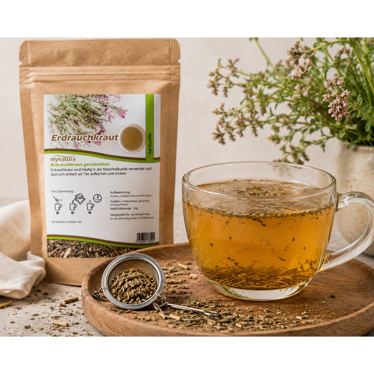 Zubereitungsszene mit einer Tasse Tee aus erdrauchkraut, daneben ein Teesieb mit geschnittenem kraut und der geöffnete Beutel im Hintergrund.